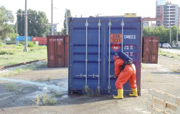 Спасатель «ЭКОСПАС» в газозащитном костюме открывает контейнер